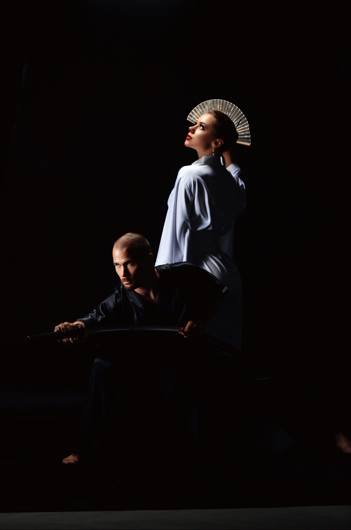 Two performers — one in white, one in black — light and shadow on one stage